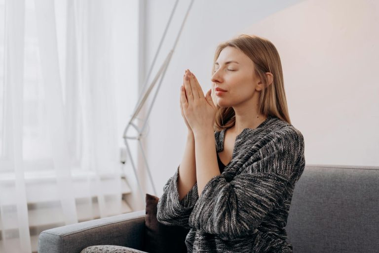 A woman meditates peacefully indoors, seeking relaxation and inner peace through mindful practices.
